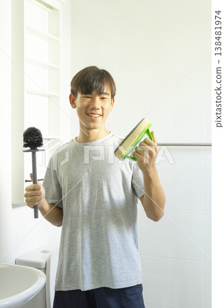Asian young teen boy cleaning bathroom at home. Asian young teen boy cleaning bathroom at home. 138481974