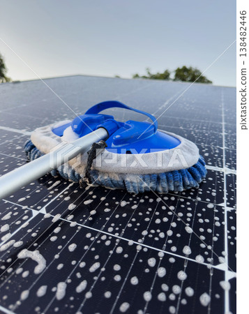 Cleaning a solar panel on a rooftop during clear weather 138482446