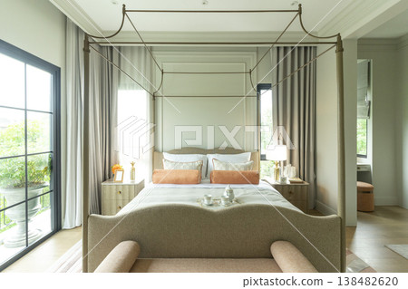 Interior view of King Size Canopy Bed Frame with pillows in elegant bedroom. Honeymoon suite bedroom in pastel and pink color Interior view of King Size Canopy Bed Frame with pillows in elegant bedroom. Honeymoon suite bedroom in pastel and pink color 138482620