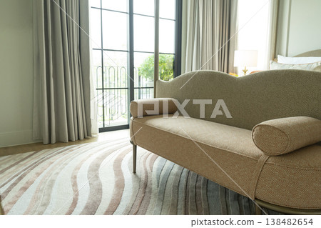 Detail of a bedroom with pastel freeform pattern rug and cozy bench. Detail of a bedroom with pastel freeform pattern rug and cozy bench. 138482654