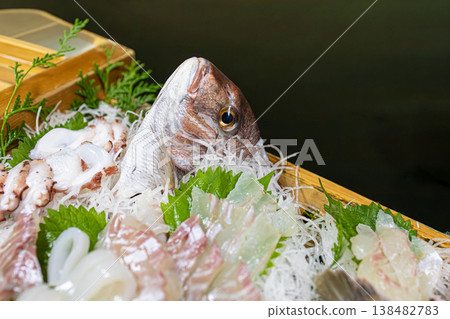 A close-up of a magnificent boat-shaped platter of whole sea bream and octopus sashimi. A close-up of a magnificent boat-shaped platter of whole sea bream and octopus sashimi. 138482783