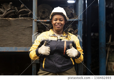 Technician African black women worker standing and smile in garage scrap yard old car part warehouse. Technician African black women worker standing and smile in garage scrap yard old car part warehouse. 138482893