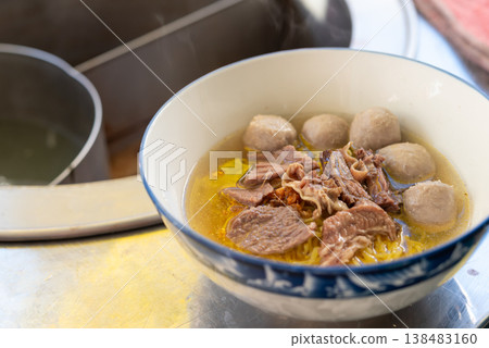 thai beef noodle soup with sliced beef and meatballs in rich broth served hot in bowl street food favorite on table savory comfort meal thai beef noodle soup with sliced beef and meatballs in rich broth served hot in bowl street food favorite on table savory comfort meal 138483160