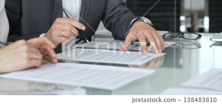 Businessman signing contract documents while female colleague is clapping, finalizing successful partnership agreement. Business people concept 138483810