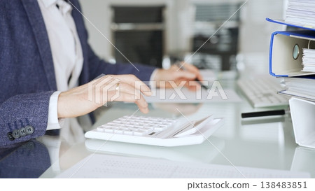 Professional accountant calculating finances and managing paperwork on an office desk, analyzing taxes and budget planning. Audit and taxes in business Professional accountant calculating finances and managing paperwork on an office desk, analyzing taxes and budget planning. Audit and taxes in business 138483851