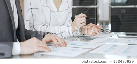 Business colleagues seated around a meeting table, discussing financial reports and performance charts. Professional office environment, teamwork concept Business colleagues seated around a meeting table, discussing financial reports and performance charts. Professional office environment, teamwork concept 138483929