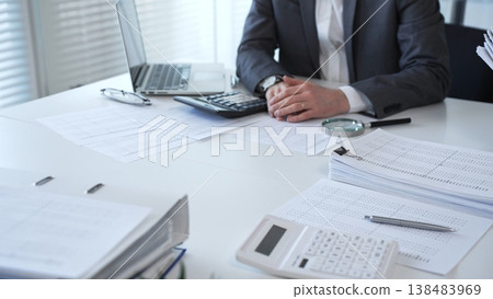 Accountants processing financial documents and working on tax audit calculations in an office setting. Audit and taxes in business Accountants processing financial documents and working on tax audit calculations in an office setting. Audit and taxes in business 138483969