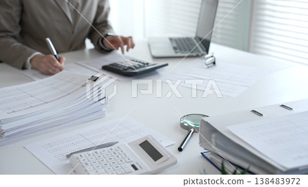 Businesswomen handle financial calculations, bookkeeping, and tax returns in the office. Audit and taxes in business 138483972