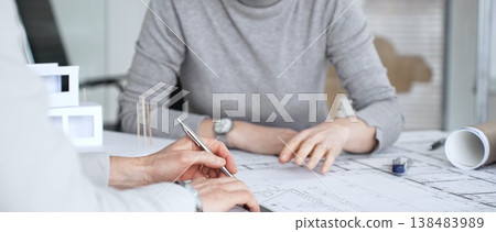 Architects discussing blueprints and a structural model on a desk, focusing on design concepts, project planning, and architectural development during an office meeting, close up Architects discussing blueprints and a structural model on a desk, focusing on design concepts, project planning, and architectural development during an office meeting, close up 138483989