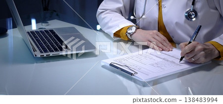 Doctor writing prescription, medical record, or healthcare report at clinic, showing professional physician completing patient information for diagnosis and treatment 138483994