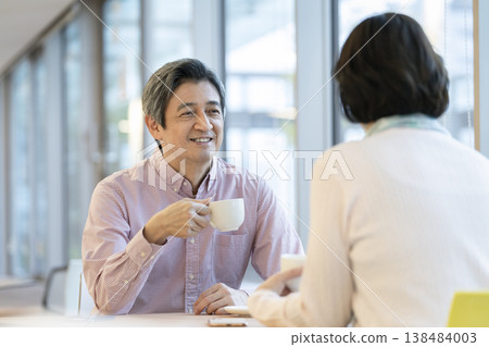 Image of a couple in their 60s relaxing at a cafe. Image of a couple in their 60s relaxing at a cafe. 138484003