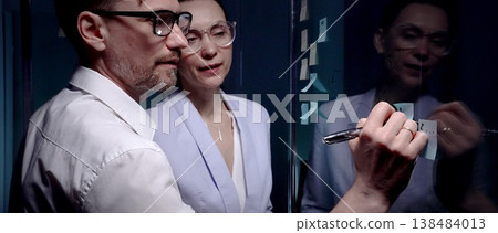 Professional business people collaborating on strategy, planning a project and developing ideas on a glass board with sticky notes in a dark modern office, working with innovative solutions Professional business people collaborating on strategy, planning a project and developing ideas on a glass board with sticky notes in a dark modern office, working with innovative solutions 138484013