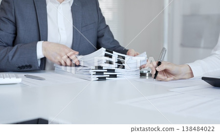 Business people preparing financial documents and signing reports at office desk, analyzing taxation data. Audit and taxes in business Business people preparing financial documents and signing reports at office desk, analyzing taxation data. Audit and taxes in business 138484022