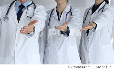Medical team offering helping hands, extending invitation for support and showing professional care, welcoming patients to healthcare services with open palms 138484126
