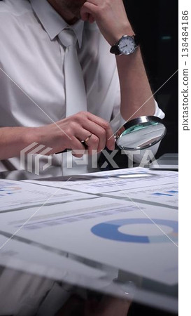 Businessman holding a magnifying glass and checking financial data, reviewing corporate audit reports, and analyzing various charts. Audit and taxes in business Businessman holding a magnifying glass and checking financial data, reviewing corporate audit reports, and analyzing various charts. Audit and taxes in business 138484186