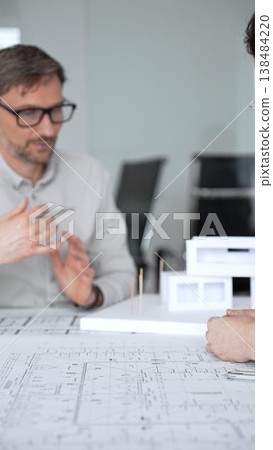 Architects and designer planning a modern house building project, collaborating on construction blueprints and architectural model in a professional office, close up Architects and designer planning a modern house building project, collaborating on construction blueprints and architectural model in a professional office, close up 138484220