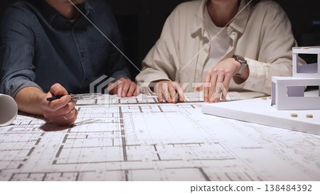 Architects team discussing building blueprint design, collaborating on construction project plans, working on architectural development at night, creating new property layouts Architects team discussing building blueprint design, collaborating on construction project plans, working on architectural development at night, creating new property layouts 138484392