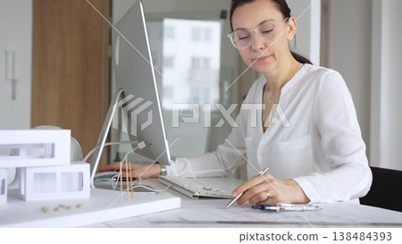 Woman architect working on desktop computer, typing and designing building plans in modern office. Business and architecture concept Woman architect working on desktop computer, typing and designing building plans in modern office. Business and architecture concept 138484393