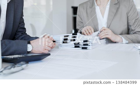 Business people hands reviewing stacks of financial papers and agreements, discussing data during an office meeting. Audit and taxes in business Business people hands reviewing stacks of financial papers and agreements, discussing data during an office meeting. Audit and taxes in business 138484399