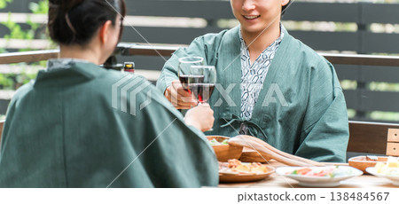 Young Asian couple at a Japanese inn or hot spring inn having a meal on the balcony or wooden deck (travel and travel) 138484567