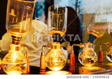 A close-up of the elegant process of a professional brewing coffee using a siphon coffee maker in a specialty coffee shop. 138484618