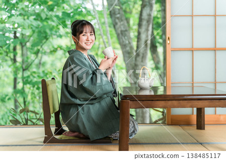 Young Asian woman in yukata drinking tea in a Japanese-style room at a ryokan Young Asian woman in yukata drinking tea in a Japanese-style room at a ryokan 138485117