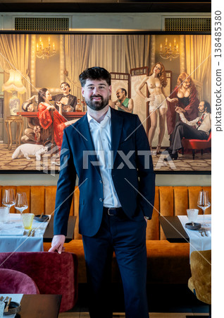Male waiter in suit smiling closeup, friendly brand ambassador vibe for hospitality campaign with warm tones and editorial framing 138485380
