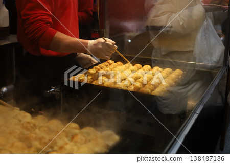 Fresh takoyaki balls being cooked on a hot iron pan at a Japanese market. 138487186