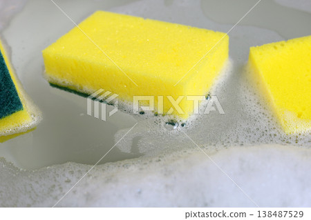 A dishwashing sponge floats in the foamy water of a dishwashing solution. A dishwashing sponge floats in the foamy water of a dishwashing solution. 138487529
