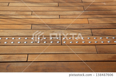 Brown wood surface with rows of metallic bolts on planks. Brown wood surface with rows of metallic bolts on planks. 138487606