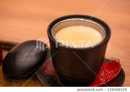 Steamed eggs served in a black bowl with spoon. Japanese food Steamed eggs served in a black bowl with spoon. Japanese food 138488326