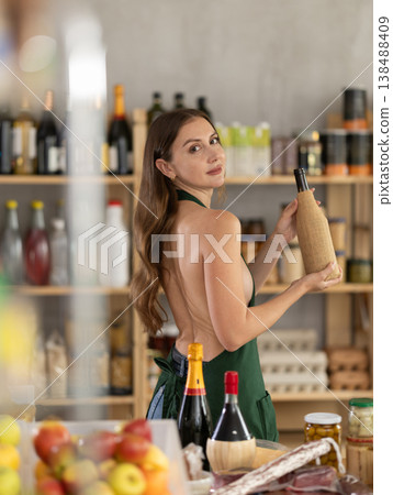 Naked two-room saleswoman in an apron offers to buy alcohol and food in supermarket Naked two-room saleswoman in an apron offers to buy alcohol and food in supermarket 138488409