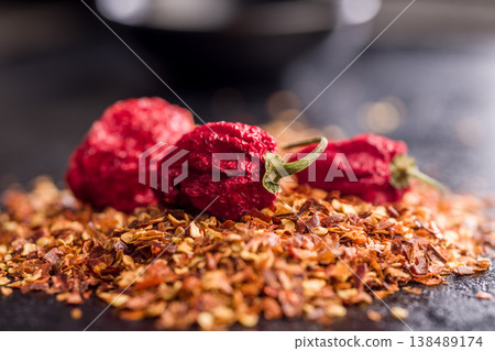 Dried Red Chili Peppers and Crushed Red Pepper Flakes Close-Up on Dark Surface 138489174