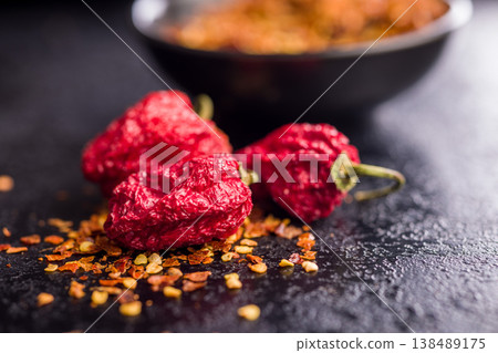 Dried Red Chili Peppers and Crushed Red Pepper Flakes Close-Up on Dark Surface 138489175