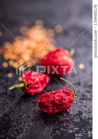 Dried Red Chili Peppers and Crushed Red Pepper Flakes Close-Up on Dark Surface 138489176