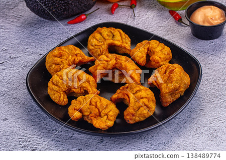 Fried dumplings Momo on a plate with creamy sauce, avocado, and chili peppers 138489774