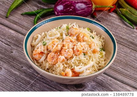 Shrimp and calamari rice with green onions in a white bowl on a rustic wooden table. Shrimp and calamari rice with green onions in a white bowl on a rustic wooden table. 138489778