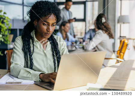 Woman intently reviewing spreadsheets on her laptop in bright workspace Woman intently reviewing spreadsheets on her laptop in bright workspace 138489920