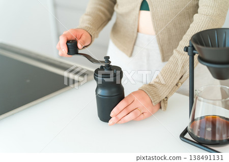 一位亞洲女性正在自家廚房用咖啡研磨機研磨咖啡豆。 一位亞洲女性正在自家廚房用咖啡研磨機研磨咖啡豆。 138491131