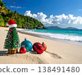 Miniature Christmas tree with santa hat and colorful ornaments on tropical beach sand with turquoise ocean and palm trees for holiday vacation and exotic celebration concepts 138491480