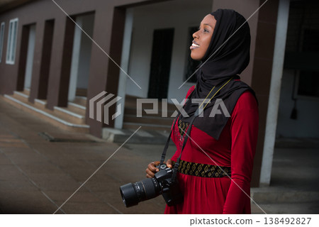 portrait of young muslim woman with camera, smiling. 138492827