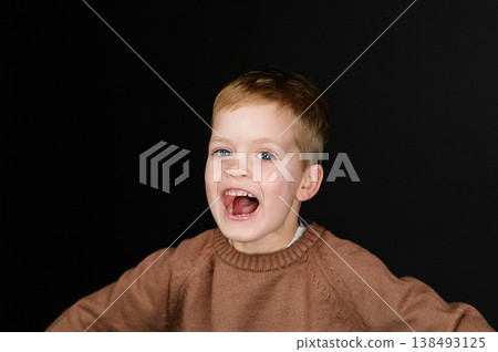Close up portrait happy child smiling on dark background. Portrait of cute child looking at camera on dark background. Minimal dark background emphasizing natural beauty and childhood innocence. Close up portrait happy child smiling on dark background. Portrait of cute child looking at camera on dark background. Minimal dark background emphasizing natural beauty and childhood innocence. 138493125