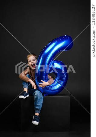 Happy child holding blue number six balloon birthday celebration concept. Birthday celebration concept with joyful and festive mood on dark background. Happy child holding blue number six balloon birthday celebration concept. Birthday celebration concept with joyful and festive mood on dark background. 138493127