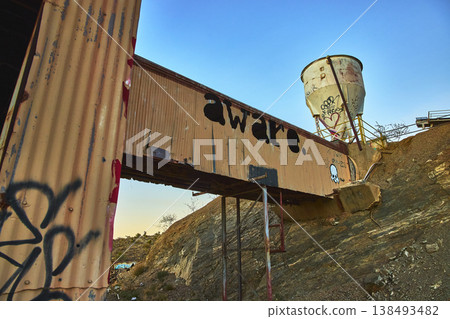 Abandoned Desert Mill Walkway With Graffiti and Rusted Tank at Sunset Abandoned Desert Mill Walkway With Graffiti and Rusted Tank at Sunset 138493482