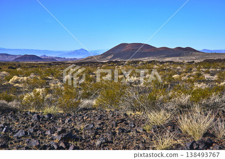 Volcanic Cinder Cones Desert Vegetation and Rocky Terrain Under Blue Sky Volcanic Cinder Cones Desert Vegetation and Rocky Terrain Under Blue Sky 138493767