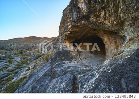 Cave Entrance in Rocky Desert Landscape with Expansive Valley and Rugged Terrain Cave Entrance in Rocky Desert Landscape with Expansive Valley and Rugged Terrain 138493848