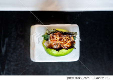 Luxurious fish amuse bouche resting on lime and ceramic with glossy reflections and crunchy topping 138494089