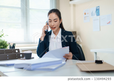 Legal and business consultant talking on smartphone while reviewing contract for client consultation Legal and business consultant talking on smartphone while reviewing contract for client consultation 138494293