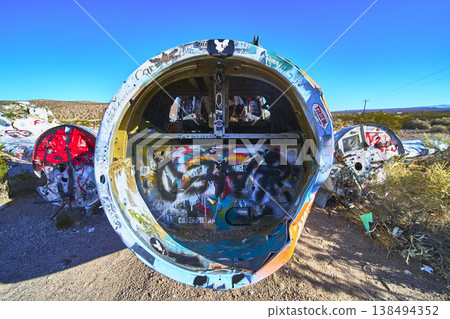Graffiti Covered Airplane Wreckage in Nevada Desert with Blue Sky and Dry Landscape Graffiti Covered Airplane Wreckage in Nevada Desert with Blue Sky and Dry Landscape 138494352