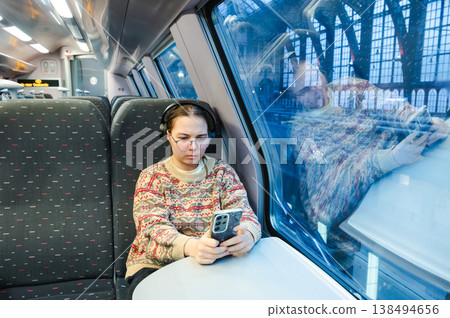 Smiling teenager girl with gallses and headphones in train Smiling teenager girl with gallses and headphones in train 138494656